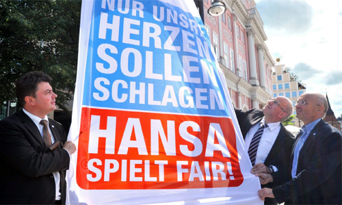 Bernd Hofmann, Roland Methling und Vorstandsmitglied Dr. Peter Zeggel mit der ersten Kampagnen-Flagge vor dem Rathaus. Foto: Joachim Kloock